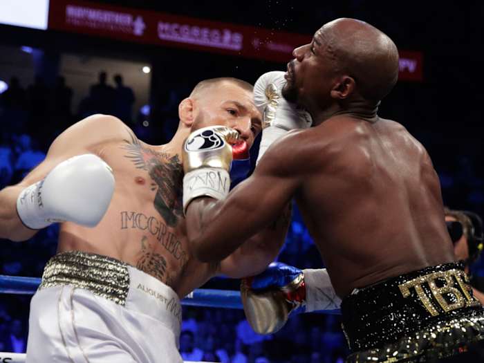 Conor McGregor hits Floyd Mayweather Jr. in a super welterweight boxing match Saturday, Aug. 26, 2017, in Las Vegas. (AP Photo/Isaac Brekken)